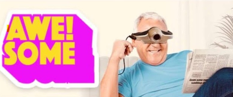 Pink and yellow AWESOME! sticker beside a bloke reading a newspaper and wearing a monocular device