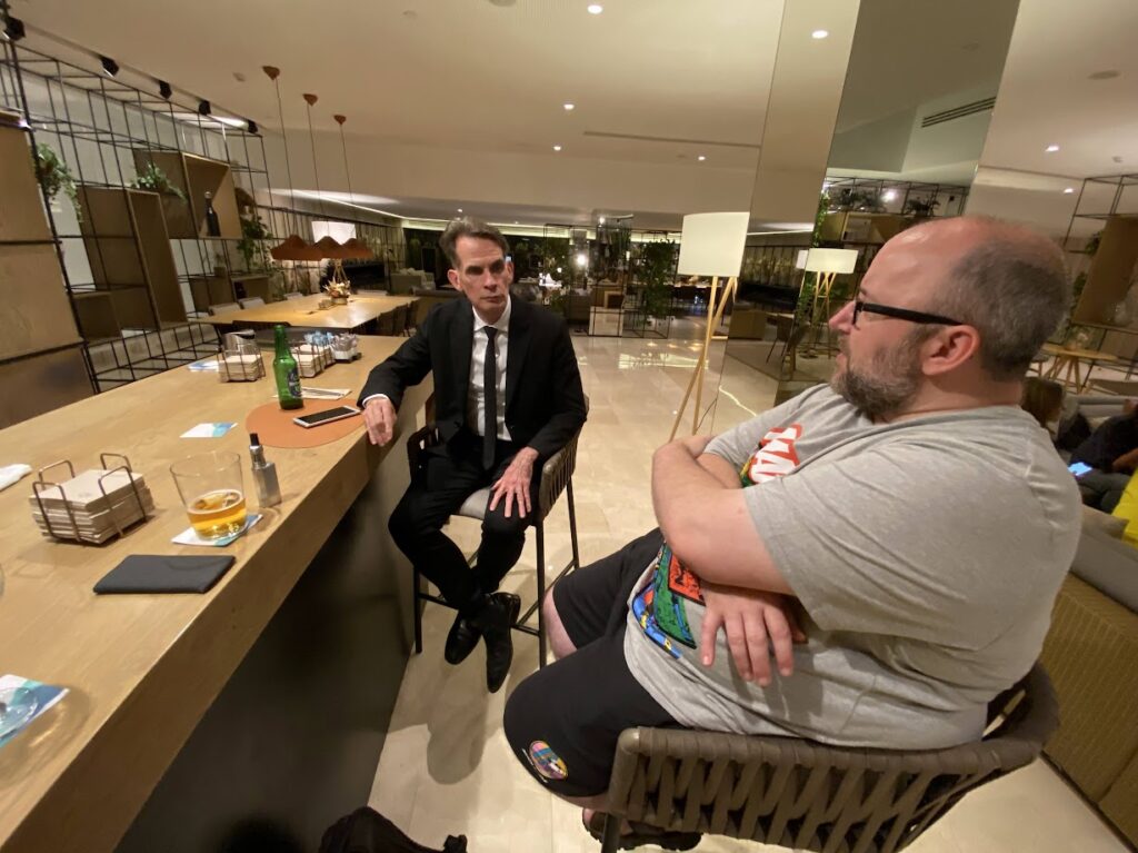 Mike interrogating Patrick at Hotel bar in Seville, he is investigating a suspected breach of the COC by Patrick