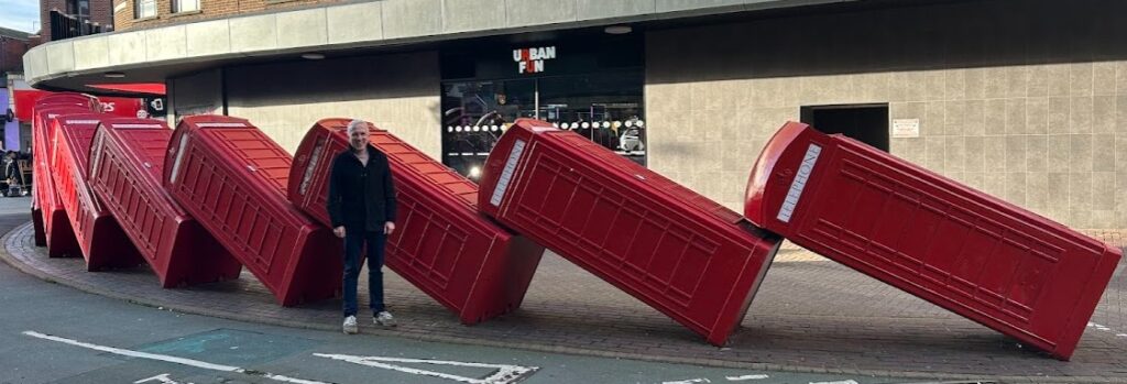 David Swallow standing in front of the toppling phone boxes in Kingston Upon Thames