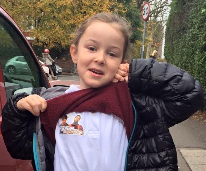 my daughter pulling up her school jumper to reveal a V&L sticker on her shirt in 2015