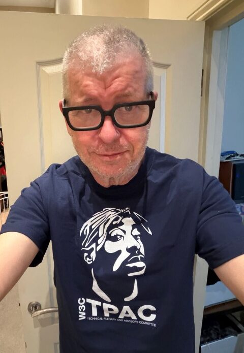 Me wearing a navy blue t-shirt, one of Lauke's originals: line art of TUPAC with "W3C TPAC Technical Plenary and Advisory Committee" text below.